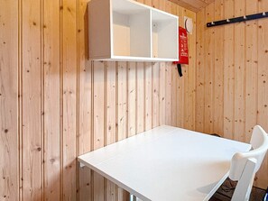 Una habitación con una mesa y una silla blancos, un armario blanco y un letrero rojo de seguridad contra incendios en la pared.