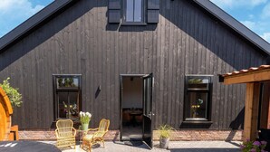 A rustic barn-style building with a sloped roof, large windows, and a brick foundation.