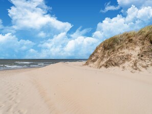 A sandy beach with a grassy dune and the ocean in the background. - Nice Holiday Home in Callantsoog With Wellness (Callantsoog)