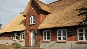 A traditional brick house with a thatched roof and a small garden. - Apartment in Ganzlin (Klanxbuell)