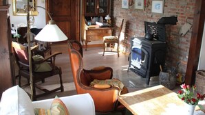 A traditional living room with a fireplace, wooden furniture, and a brick wall. - Apartment in Ganzlin (Klanxbuell)