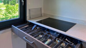 A modern kitchen with a built-in stove, a stainless steel range hood, and a window with a view of greenery. - Eco-friendly Villa With Terrace and Garden (Dirkshorn)