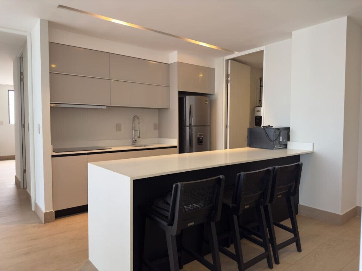 A modern kitchen with a central island, stainless steel appliances, and a bar area with chairs.