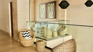 A modern interior with wicker furniture, a glass railing, and decorative wall art.