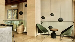 A modern interior with a glass partition, wicker furniture, and geometric wall art.