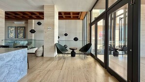 A modern interior with a marble counter, two black chairs, and a glass partition.