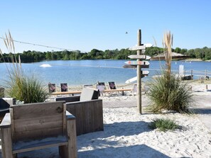 Een gebied aan het strand met houten banken en een bord met richting pijlen.
