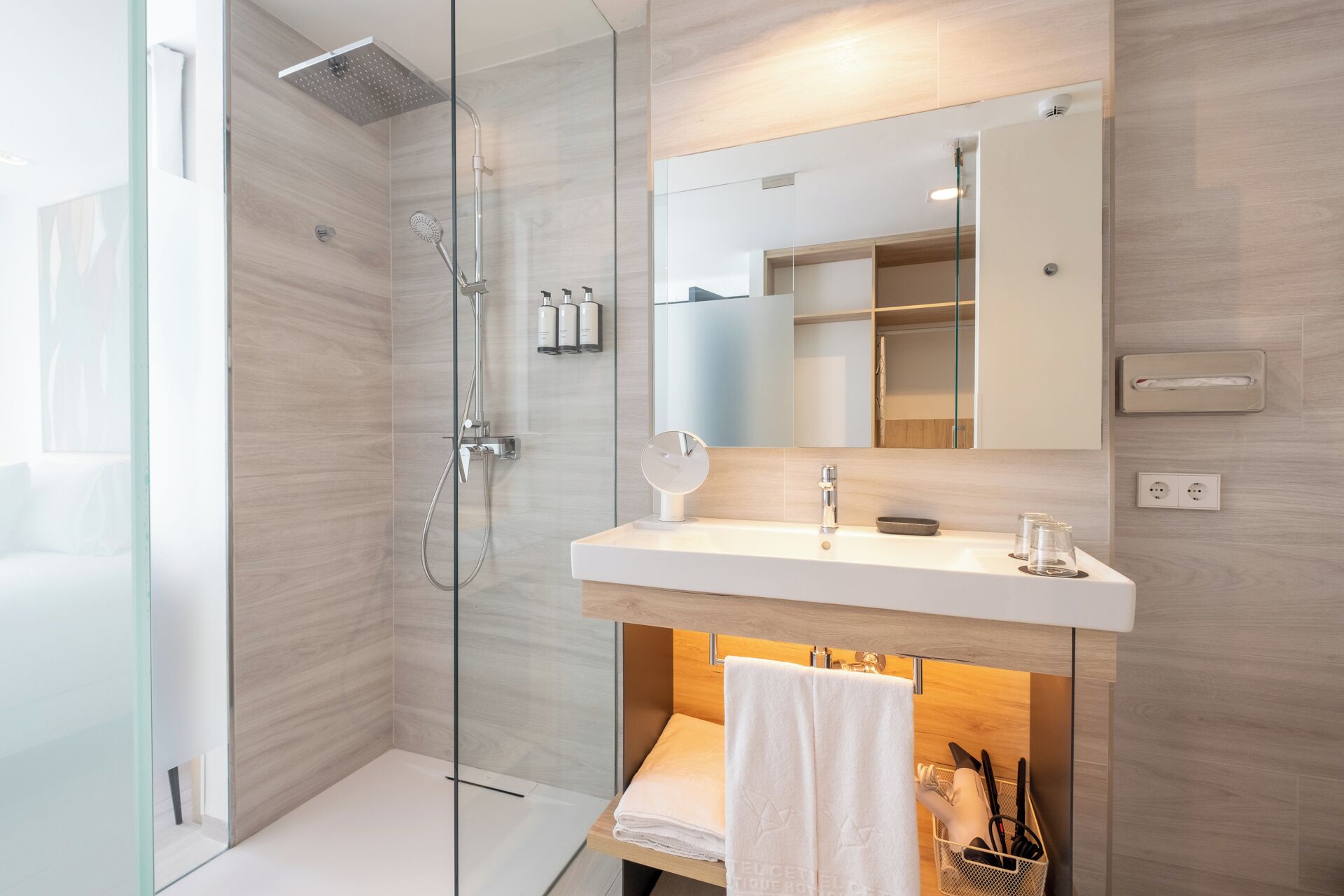 A modern bathroom with a glass shower enclosure, a white vanity with a mirror, and a towel rack.