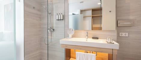 A modern bathroom with a glass shower enclosure, a white vanity with a mirror, and a towel rack.