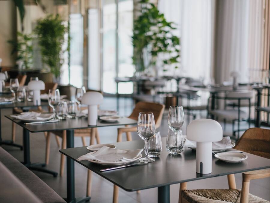 A restaurant with tables set for dining, featuring clear glassware and white tableware.
