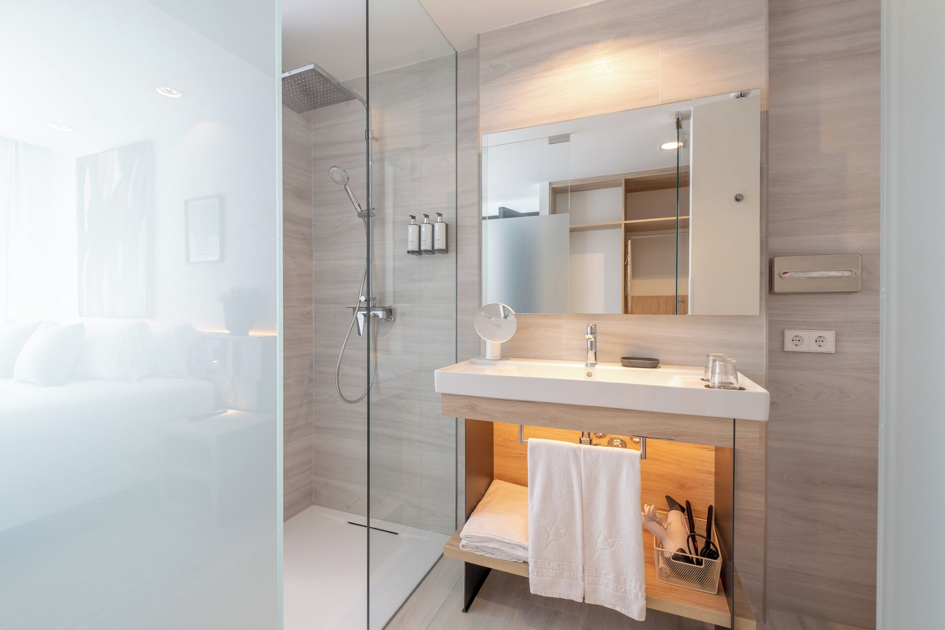 Un baño moderno con cabina de ducha de vidrio, tocador blanco con espejo y toallero.