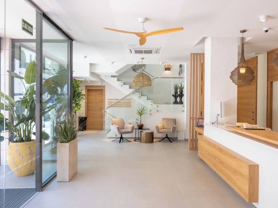 A modern reception area with a wooden reception desk, a staircase, and potted plants.