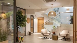 A modern lobby with a staircase, seating area, and a large plant.