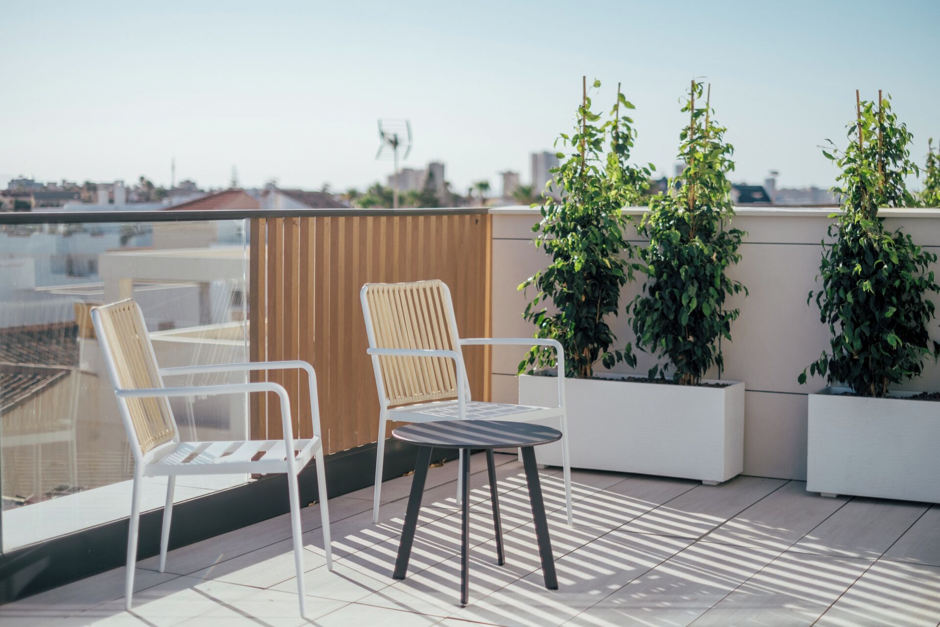 Une terrasse sur le toit, avec deux chaises et une table, entourée de plantes en pot.