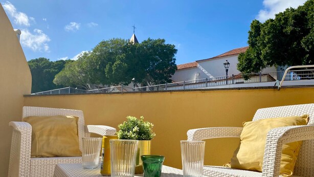 A patio with wicker furniture and a small table, a potted plant, and a clear glass. - Casa Amplia y Espaciosa Para Descubrir un Tenerife Auténtico y Local (San Miguel)
