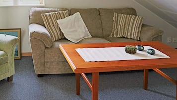 A living room with a sofa, a wooden coffee table, and a framed picture on the wall.