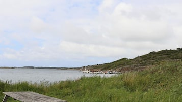 A picnic table by a body of water with boats in the background.