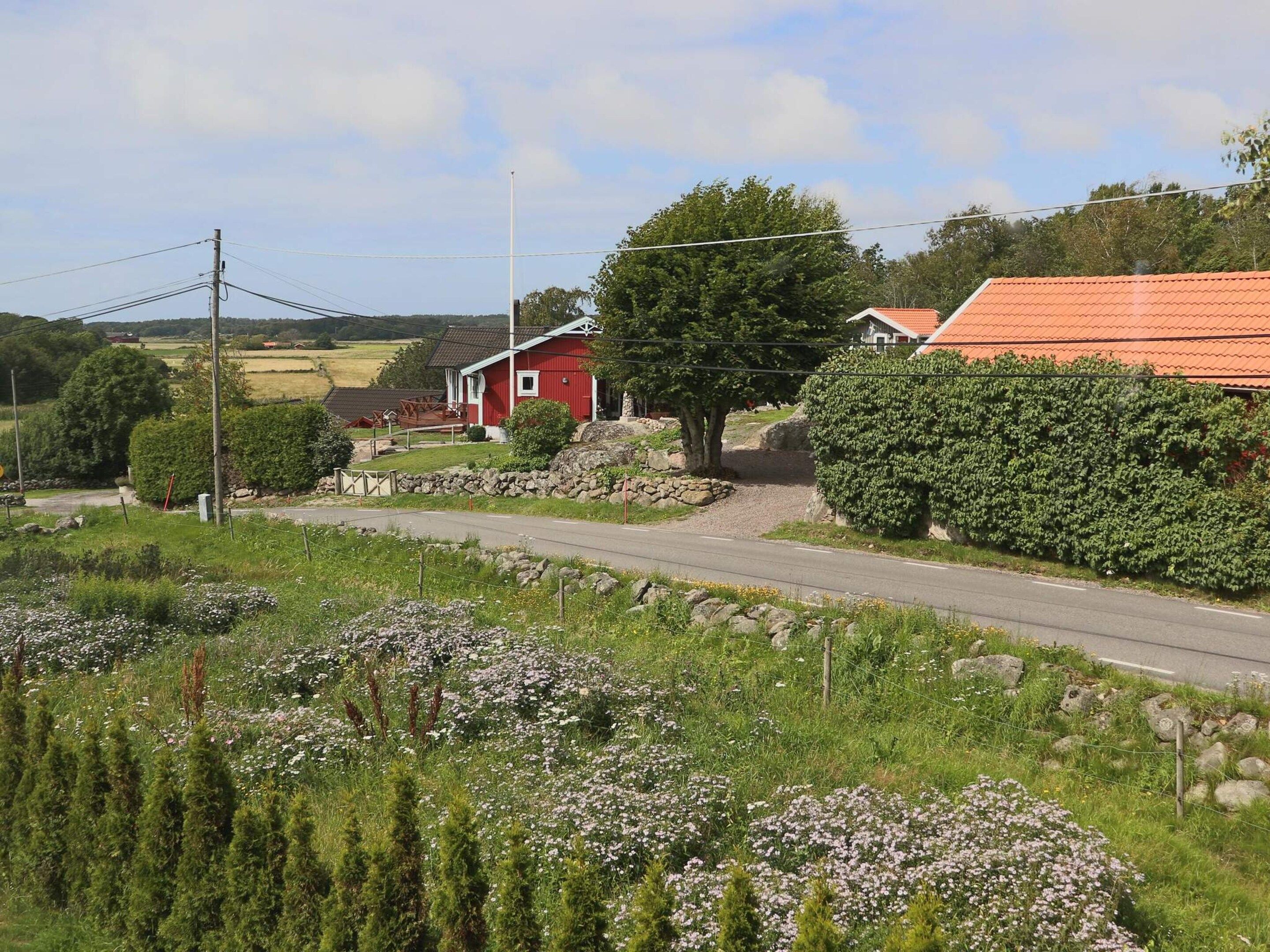 A rural road with a red house and a stone wall.