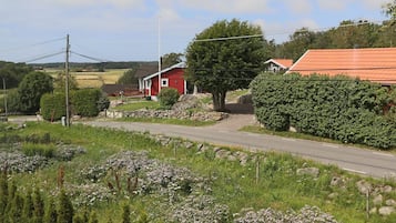 A rural road with a red house and a stone wall.
