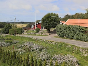 Un camino rural con una casa roja y un muro de piedra.