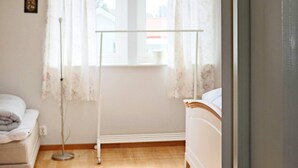 A bedroom with a bed, a bedside table, a window with curtains, and a radiator. - 4 Person Holiday Home in Onsala (Gottskar)