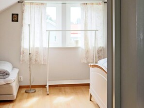 A bedroom with a bed, a bedside table, a window with curtains, and a radiator. - 4 Person Holiday Home in Onsala (Gottskar)