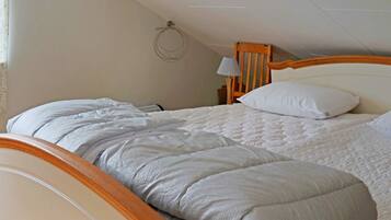 A single bed with a wooden headboard and a white quilted bedspread.