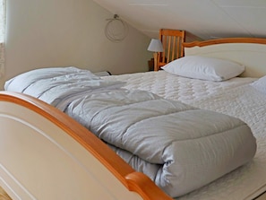 Un lit simple avec une tête de lit en bois et une couvre-lit blanche matelassée.