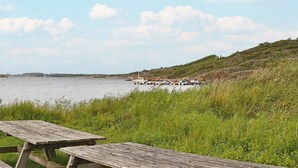 A lakeside picnic area with wooden benches and a view of boats on the water. - 4 Person Holiday Home in Onsala (Gottskar)