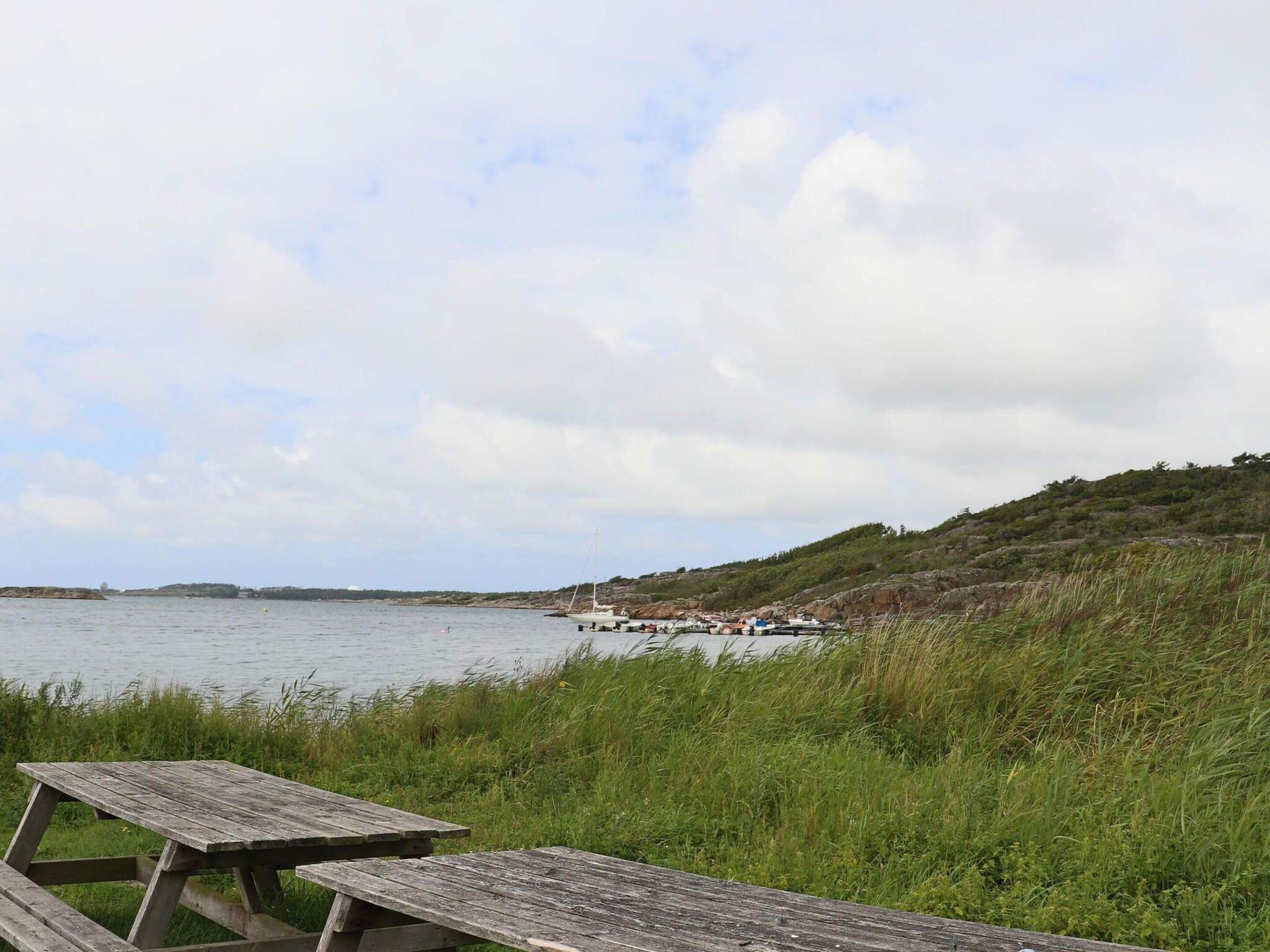 A picnic table by a lake with boats in the background.