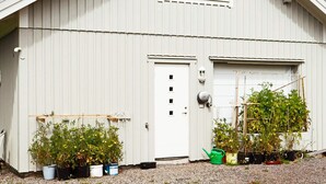 A white building with a garage door, a small window, and several potted plants in front. - 4 Person Holiday Home in Onsala (Gottskar)