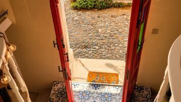 A staircase leading to a door with an emergency exit sign, a small potted plant, and patterned tiles.