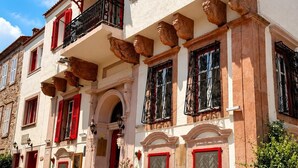 A building with red shutters, a balcony, and a signboard. - Cunda Bebekli Ev (Ayvalik)