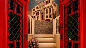 A staircase with red doors and a view of a building through a mural. - Cunda Bebekli Ev (Ayvalik)