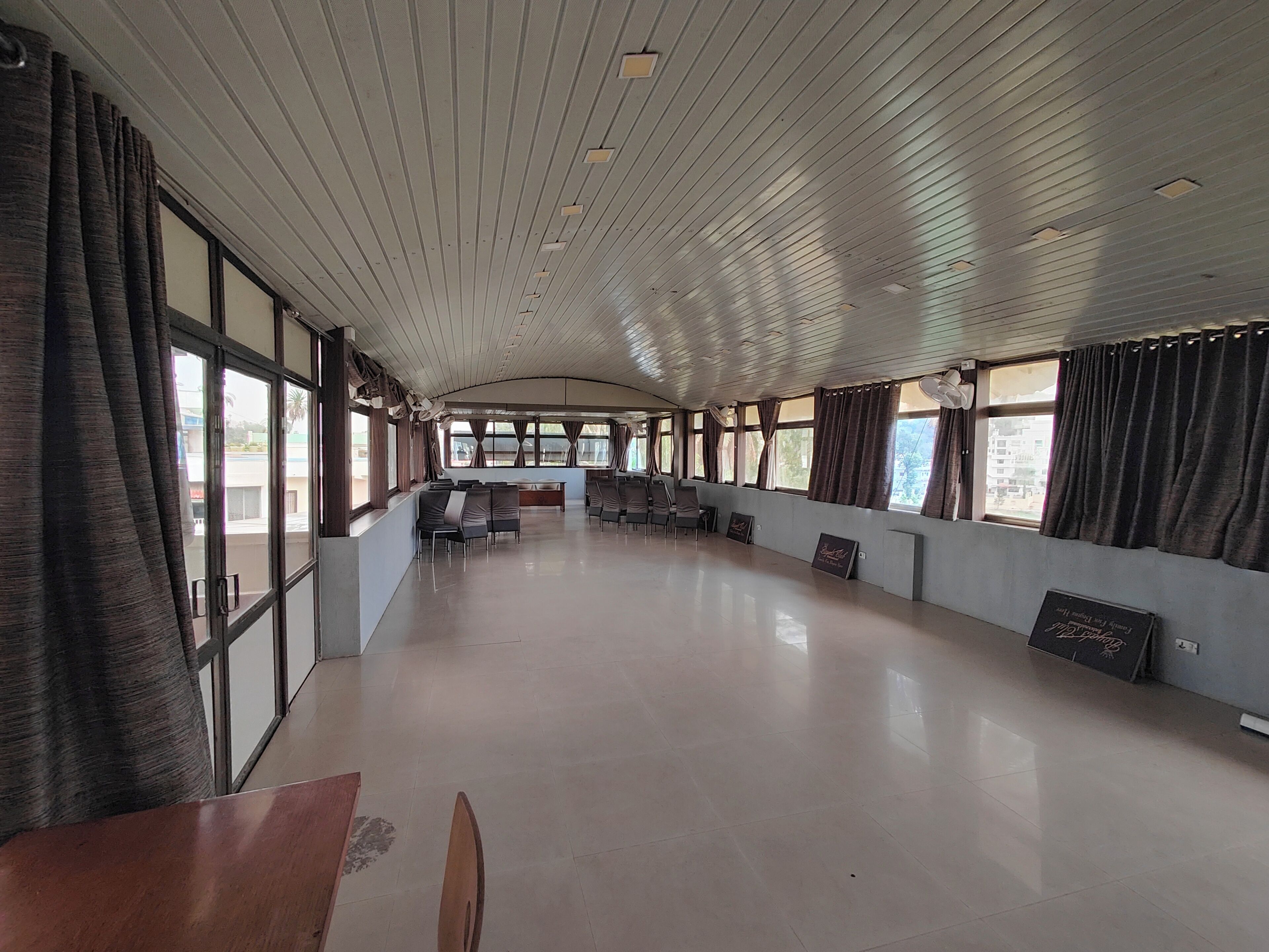 A spacious hall with a high ceiling, large windows, and rows of chairs.
