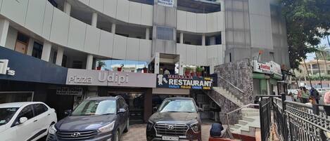 A multi-story building with a restaurant named "MAHARAJI RESTAURANT" and a pizza place called "PIZZA Udipi".