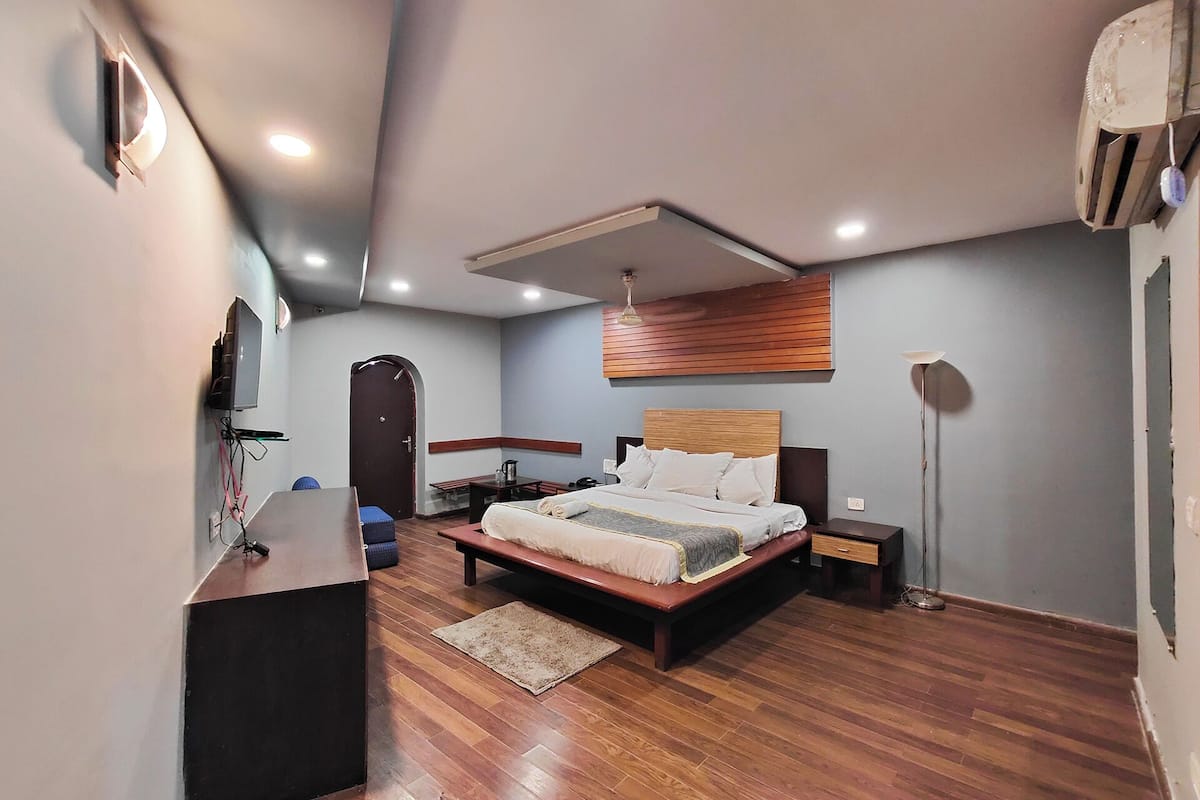A modern bedroom with a wooden bed, a desk, and a standing lamp.