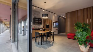 Una cucina moderna con zona pranzo, televisione e un'ampia pianta in vaso.