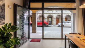 L'ingresso di un hotel con una porta in vetro, un tavolo di legno con calici da vino e vista su auto parcheggiate all'esterno.