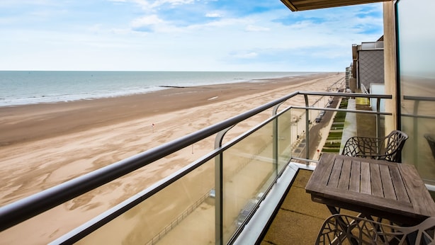Ein Balkon mit Blick auf einen Sandstrand und das Meer.