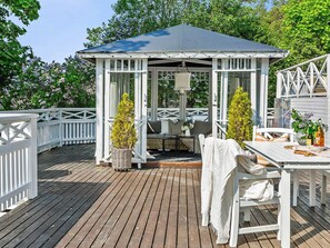 A gazebo with a white exterior and a blue roof, surrounded by a wooden deck and white railings. - 5 Star Holiday Home in Odsmal (Oedsmal)