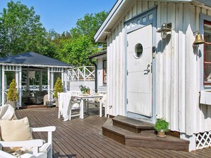 A white wooden building with a porch, a covered seating area, and a small table with chairs. - 5 Star Holiday Home in Odsmal (Oedsmal)