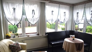 A room with a sofa, a table, and a window with curtains. - Sonniges Dachgeschoss-refugium, Wildemann (Clausthal-Zellerfeld)