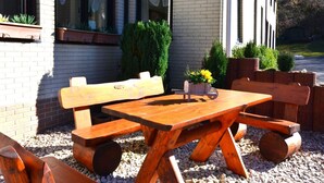 An outdoor wooden table and benches set against a building with windows and planters. - Sonniges Dachgeschoss-refugium, Wildemann (Clausthal-Zellerfeld)