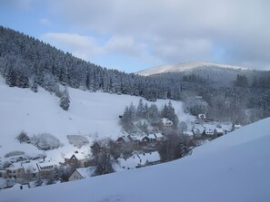 Un village enneigé, avec des maisons traditionnelles et une montagne en arrière-plan.