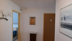 A hallway with a wooden floor, a door, a small trash bin, a framed picture on the wall, and a decorative metal piece. - Sonniges Dachgeschoss-refugium, Wildemann (Clausthal-Zellerfeld)