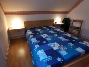 Een slaapkamer met een bed, twee bedlampen, een stoel en een nachtkastje.