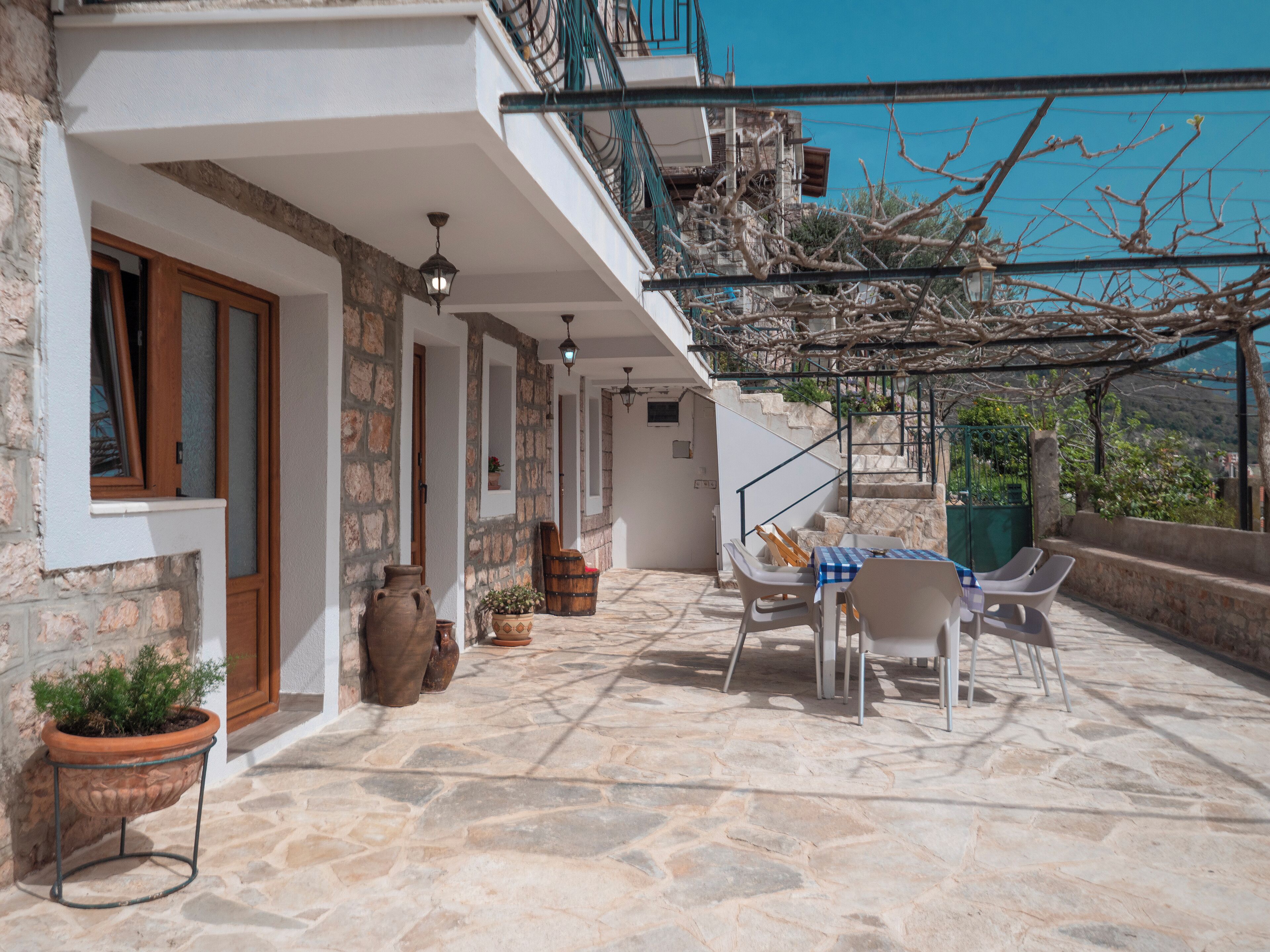 A stone-floored patio with outdoor furniture, a staircase, and a view of the surrounding landscape.