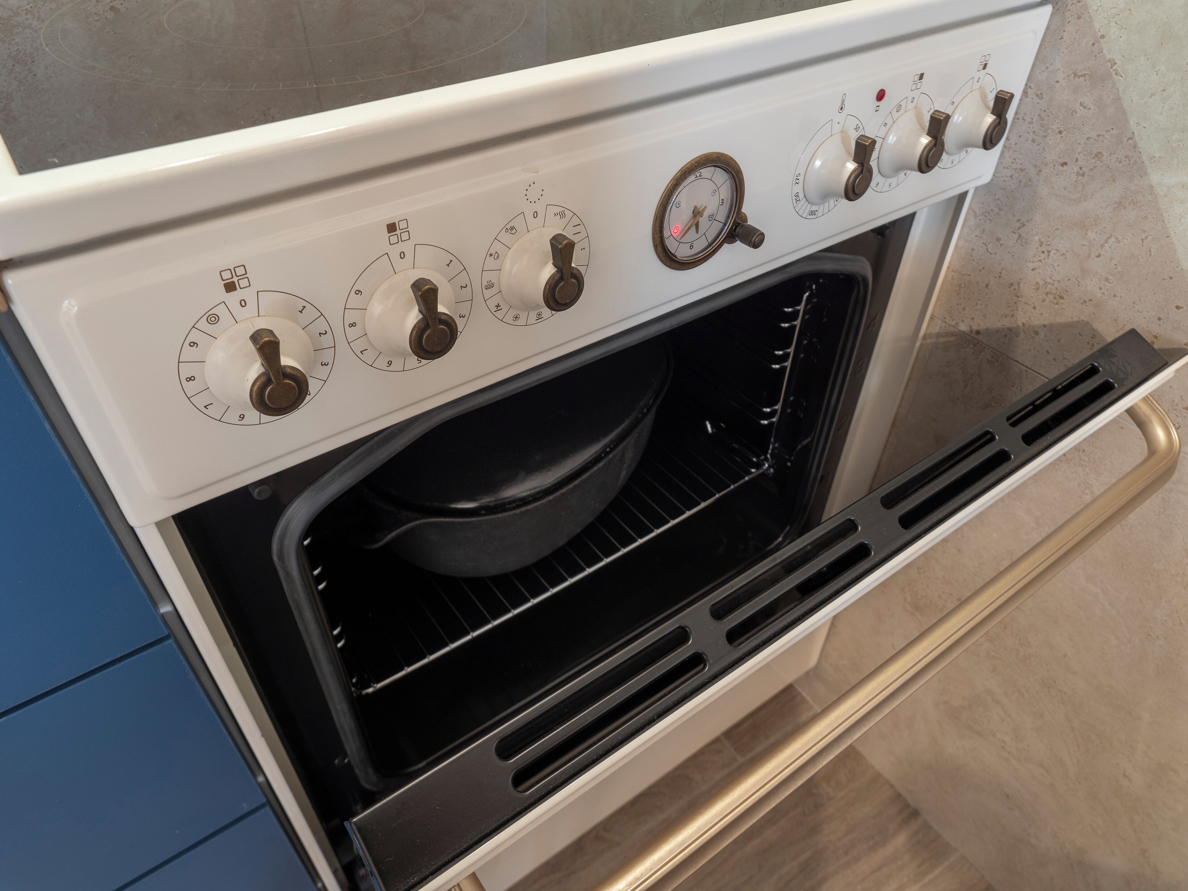Una cocina con estufa y horno, incluyendo perillas de control y un indicador de presión.
