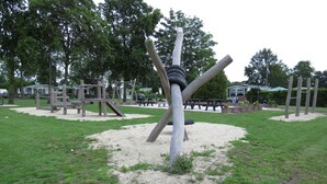 A playground with a tire swing structure, sandpit, and picnic tables. - Cozy Chalet on a Holiday Park Near Alkmaar (Hensbroek)
